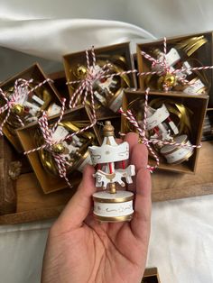 a hand is holding some small ornaments in front of boxes with gold and white decorations on them