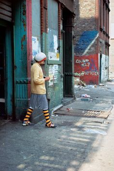 an old woman standing in front of a building with graffiti on the walls and door