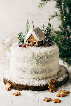 a white cake topped with frosting and gingerbreads next to a christmas tree