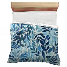 a bed with blue leaves on it next to a wooden headboard and pillow case