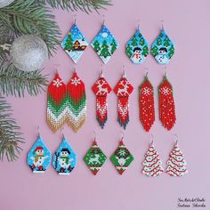 christmas themed beaded earrings hanging from a tree branch on a pink background with pine branches