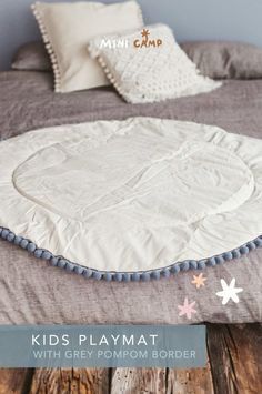 a bed with a white comforter and blue pompom border on the bottom