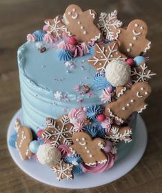 a blue frosted cake topped with lots of gingerbread cookies and snowflakes