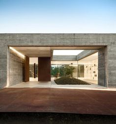 an open door leading into a room with concrete walls and floor to ceiling glass doors