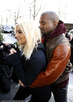 a man and woman are walking together in the street with their arms around each other