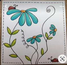 a card with flowers and ladybugs painted on the front, sitting on a table