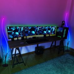 a computer desk with two monitors on it in front of a purple and blue wall