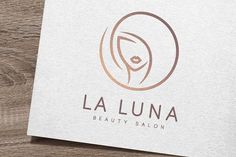 the logo for la luna beauty salon on top of a wooden table next to a cup of coffee