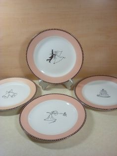 four pink and white plates with drawings on them