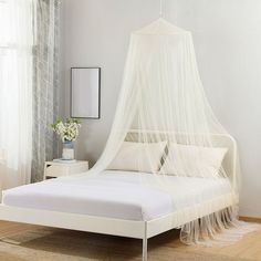 a bed with a white canopy over it in a room next to a window and rug