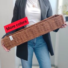 a woman holding a wicker basket with the words more colors on it and a red piece of paper in her hand