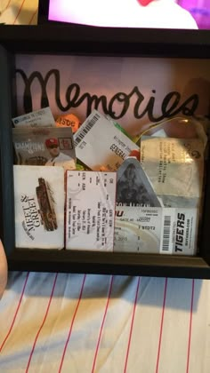 a person is holding up a box with some tickets in it and the word memories written on it