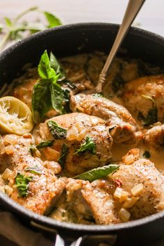 a skillet filled with chicken and spinach covered in sauce, garnished with parsley