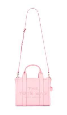 "Find MARC JACOBS The Leather Small Tote Bag In Pink on Editorialist. The Marc Jacobs Leather Small Tote Bag is crafted from full grain leather with a smooth leather lining. It features a top zipper closure, one main compartment, and an interior card slot. The bag is accented with a debossed \"The Tote Bag\" logo at the front. It has structured handles with a detachable and adjustable leather shoulder strap. The bag measures approximately 10 W x 7.5 H x 4.75 D. The shoulder strap has a 21 drop a Mark Jacobs Bag, Bag Logo, Marc Jacobs Tote, Gift Inspo, Girly Bags, Small Tote Bag, Bags Logo, Marc Jacobs Bag, The Tote Bag