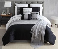 a bed with black and white comforters in a room next to a night stand