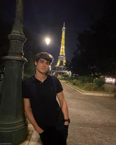 a man standing next to a lamp post in front of the eiffel tower