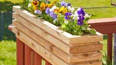 a wooden planter filled with purple and yellow flowers