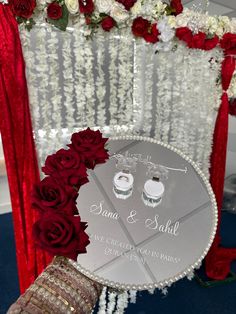 the table is decorated with red roses and white flowers, along with an umbrella that says sana & sahil