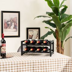 a table with a wine rack and two bottles on it next to a potted plant