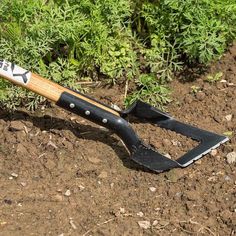 a garden tool laying on the ground next to some plants