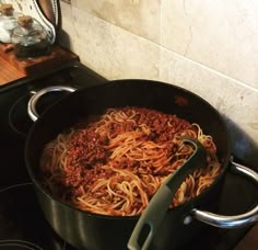 a pan filled with spaghetti sitting on top of a stove next to an oven burner