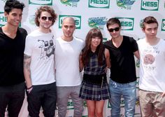 a group of young people standing next to each other in front of a green and white wall