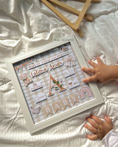 a child's hand is touching a frame with some stickers on it