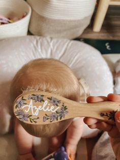 a baby holding a wooden brush with the word affle on it's side