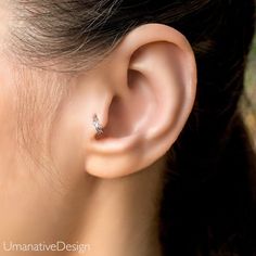 a woman's ear with a single diamond in it