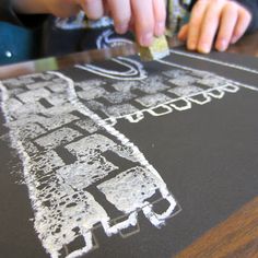 a child is drawing on a blackboard with white chalk and some type of glue