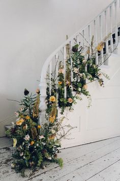 flowers and greenery are arranged on the stair case in front of a white staircase