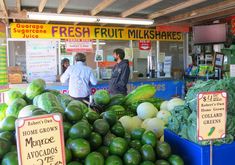 there are many fruits and vegetables on display in the market stall, including melons