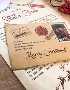 two envelopes with santa claus stamps on them sitting next to christmas decorations and glasses