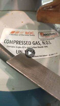 a knife sitting on top of a white plate next to a piece of paper that says compressed gas, no 5