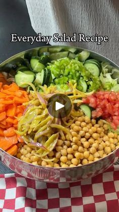 a large metal bowl filled with vegetables on top of a checkered table cloth