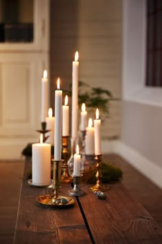 candles are lit on a wooden table in front of a wall with white walls and wood flooring