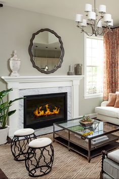 a living room filled with furniture and a fire place under a mirror on the wall