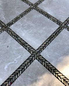 a close up view of a tile floor with braiding on the edges and in between