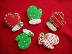 decorated cookies are sitting on a red tablecloth with white polka dots and green mittens