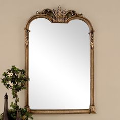 a mirror sitting on top of a table next to a potted plant