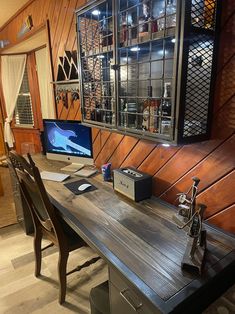 a desk with two computers on it in front of a wood paneled wall and floor