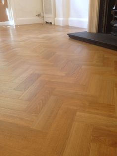 an empty room with wood floors and a fireplace