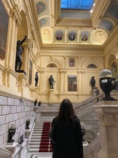 a woman is walking up the stairs in a building with paintings on the walls and ceiling