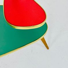 a red and green table with wooden legs on white background, showing the top part of the table