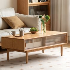 a coffee table with vases and flowers on it in front of a white couch