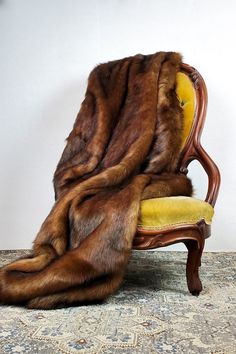 a chair with a fur stole on top of it's back and arm rest