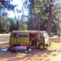 an old camper van is parked in the middle of a field with camping gear