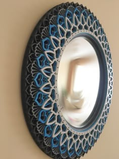 a circular mirror hanging on the wall with blue and white designs in front of it