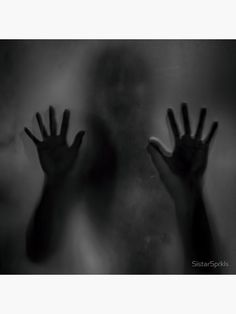 two hands reaching out from behind a glass door with the light shining on them and fog in the air