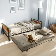 two beds in a room with white walls and wooden flooring, one has a teddy bear on the bed